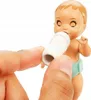 A close-up shot of a baby doll being fed a bottle by a person's fingers. Podgląd zdjęcia produktu