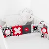 A baby crib with a plush toy and a sensory toy attached to the side. Produktbild-Vorschau