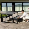 A man is interacting with a modern outdoor furniture set on a wooden deck. Produktbild-Vorschau
