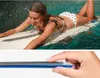 A woman is lying on a surfboard in the water, with a waterproof phone case on the surfboard. Below, a hand is holding a phone case. Podgląd zdjęcia produktu