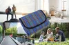 A collage of four images showing different uses of a picnic blanket: hiking, a nursery, a poolside, and a family picnic. Produktbild-Vorschau