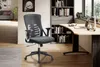 An office chair is placed in a home office setting next to a desk with a laptop and books. Voir les images du produit