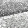 A close-up, textured view of a rug with a speckled pattern. Produktbild-Vorschau
