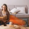A woman is reading a book while sitting on the floor near a heater. Voir les images du produit