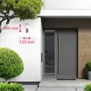 A modern house entrance with a gray door and a wall lamp. Dimensions are indicated on the wall. Produktbild-Vorschau