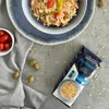 A prepared dish of orzo pasta with tomatoes and olives, next to a bag of Liakada Kritharaki orzo pasta. Podgląd zdjęcia produktu