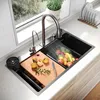 A modern kitchen sink with various accessories, including a cutting board with fruit and a faucet running water over a basket of fruit. Produktbild-Vorschau