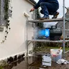 A person is using a paint roller on a wall while a gas heater is blowing hot air onto the wall. Produktbild-Vorschau