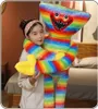 A young woman is hugging a large, rainbow-colored plush toy. Produktbild-Vorschau