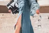 A person holding a magazine and a water bottle, wearing a denim outfit. Anteprima dell’immagine prodotto