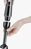 A person's hand is holding the main body of a black immersion blender, and another hand is about to attach the blending attachment. Náhled obrázku produktu