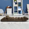 A brown floor chair is laid out on a rug in a room with blue walls and a white shelving unit. Voir les images du produit