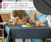 People are sitting around a table covered with a dark gray tablecloth, eating a meal. Produktbild-Vorschau