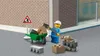 A LEGO construction worker is shown with a wheelbarrow full of bricks, a shovel, and a rat figurine on a pile of bricks, set against a brick wall and a building. Produktbild-Vorschau