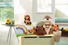 A collection of stuffed animals and a pillow are arranged on a light green toy chest in a child's room. Anteprima dell’immagine prodotto
