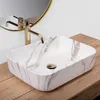 A close-up shot of a marble-patterned vessel sink with a gold faucet. Produktbild-Vorschau