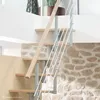 A modern staircase with wooden steps and a metal railing against a stone wall. Produktbild-Vorschau