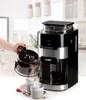 A hand is pouring coffee from a carafe into two cups next to a coffee machine. Podgląd zdjęcia produktu