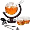 A globe-shaped decanter filled with amber liquid, resting on a wooden stand, accompanied by two glasses, a set of whiskey stones, tongs, and a funnel. Náhľad obrázku produktu