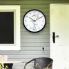 A clock is mounted on the exterior wall of a house, next to a window and a door. Náhled obrázku produktu