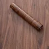 A roll of wood-effect self-adhesive wallpaper or laminate is placed diagonally on a wooden surface. Anteprima dell’immagine prodotto