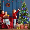 A mother and two daughters decorating a Christmas tree. Produktbild-Vorschau