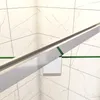 A close-up view of a shower enclosure, showing the metallic frame and glass panels against a tiled wall. Produktbild-Vorschau