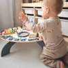A baby is playing with a colorful wooden activity table. Podgląd zdjęcia produktu
