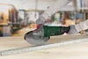 A person wearing gloves is using an angle grinder to cut a metal bar on a wooden surface. Produktbild-Vorschau