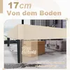 A close-up view of a bed frame leg, showing the clearance from the floor, with boxes and a suitcase in the background. Produktbild-Vorschau