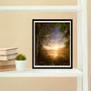 A framed picture of a sunset over a lake, framed by trees and foliage, is displayed on a white shelf next to a stack of books and a small potted plant. Anteprima dell’immagine prodotto