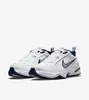 A pair of white Nike Air Monarch IV sneakers with navy blue accents and a silver Nike swoosh logo, shown against a white background. Produktbild-Vorschau