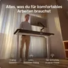 A man is standing at a height-adjustable desk in a well-lit room with sheer curtains in the background. Voir les images du produit