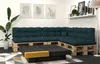 A modern living room with a sectional sofa made from pallets and dark green cushions, a dark wood coffee table with a yellow accent, and a large potted plant. Voir les images du produit