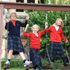 Three young girls in school uniforms are on a swing set. Produktbild-Vorschau