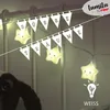 A string of star-shaped lights with German text banners hanging above a crib or bed. Náhľad obrázku produktu