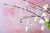 Easter ornaments shaped like bells and butterflies hang from pussy willow branches, with tulips in the background. Produktbild-Vorschau