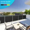 A balcony with a view of a lake and buildings, featuring a privacy screen and outdoor furniture. Produktbild-Vorschau