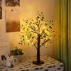 A decorative artificial tree with LED lights sits on a table covered with a patterned tablecloth. Produktbild-Vorschau