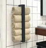 A black metal towel rack mounted on a tiled wall, holding several rolled beige towels. Anteprima dell’immagine prodotto