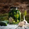 A jar of pickles with dill and garlic on a wooden surface. Voir les images du produit
