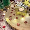 A festive Christmas scene with a wooden slice, a star-shaped candle holder, red star confetti, and fairy lights. Produktbild-Vorschau