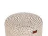 A close-up view of a round, beige, crocheted ottoman with a textured pattern. Náhled obrázku produktu