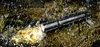 A black Fenix flashlight is lying on wet rocks, with light shining from its front. Náhled obrázku produktu