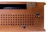 The back panel of a wooden stereo system, showing various ports and ventilation holes. Produktbild-Vorschau