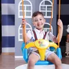A young boy is sitting on a colorful swing in what appears to be a playroom or indoor play area. Produktbild-Vorschau