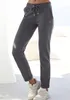 A person wearing gray sweatpants and white sneakers, standing in a bright, outdoor setting with white furniture. Produktbild-Vorschau