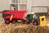 A toy tractor and trailer are placed on a bale of hay. Produktbild-Vorschau