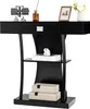 A black console table with a drawer and two shelves, decorated with a flip clock, a vase with a flower, a framed picture, a small figurine, and two decorative boxes. Náhľad obrázku produktu