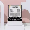 A jewelry box containing a bracelet, presented on a white pedestal against a light pink background. Voir les images du produit